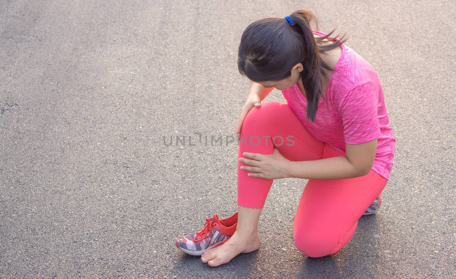 Knee Injuries. Young sport woman holding knee with her hands in pain after suffering muscle injury during a running workout at park. Healthcare and sport concept.