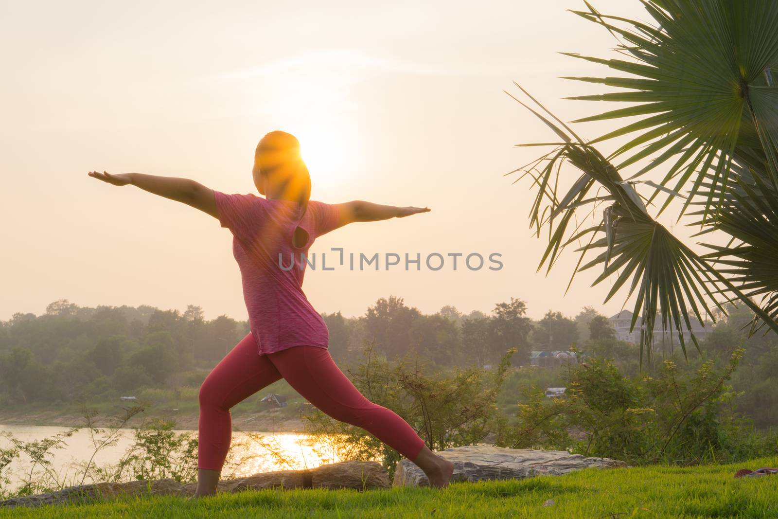 Asian woman practicing yoga in a garden. Healthy lifestyle and relaxation concept