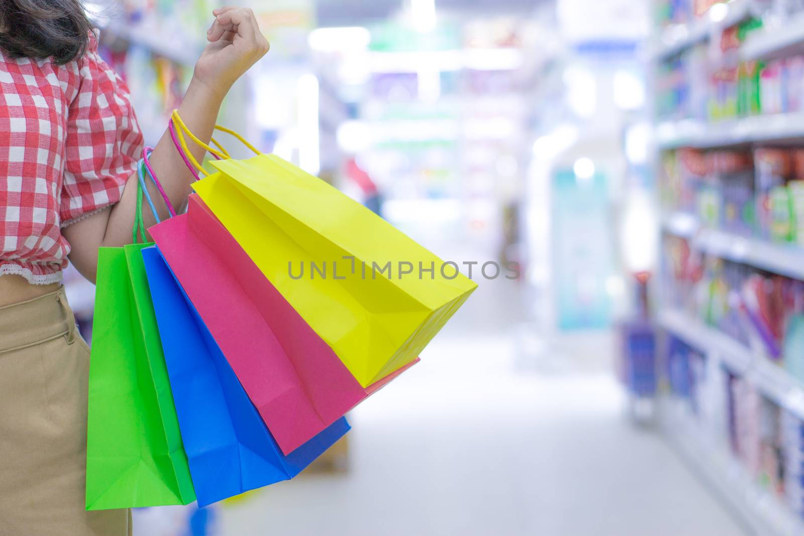 Close up woman hand holding many shopping bags in the shopping mall. Shopping concept.