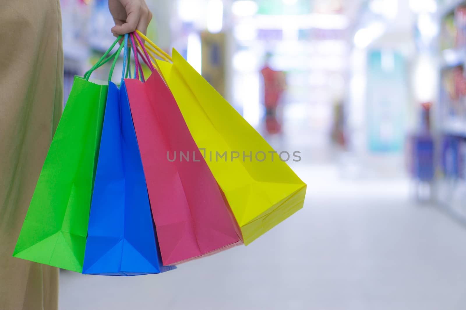 Close up woman hand holding many shopping bags in the shopping mall. Shopping concept.