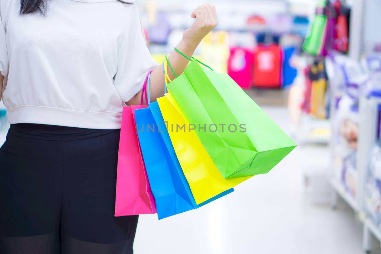 Close up woman hand holding many shopping bags in the shopping mall. Shopping concept.