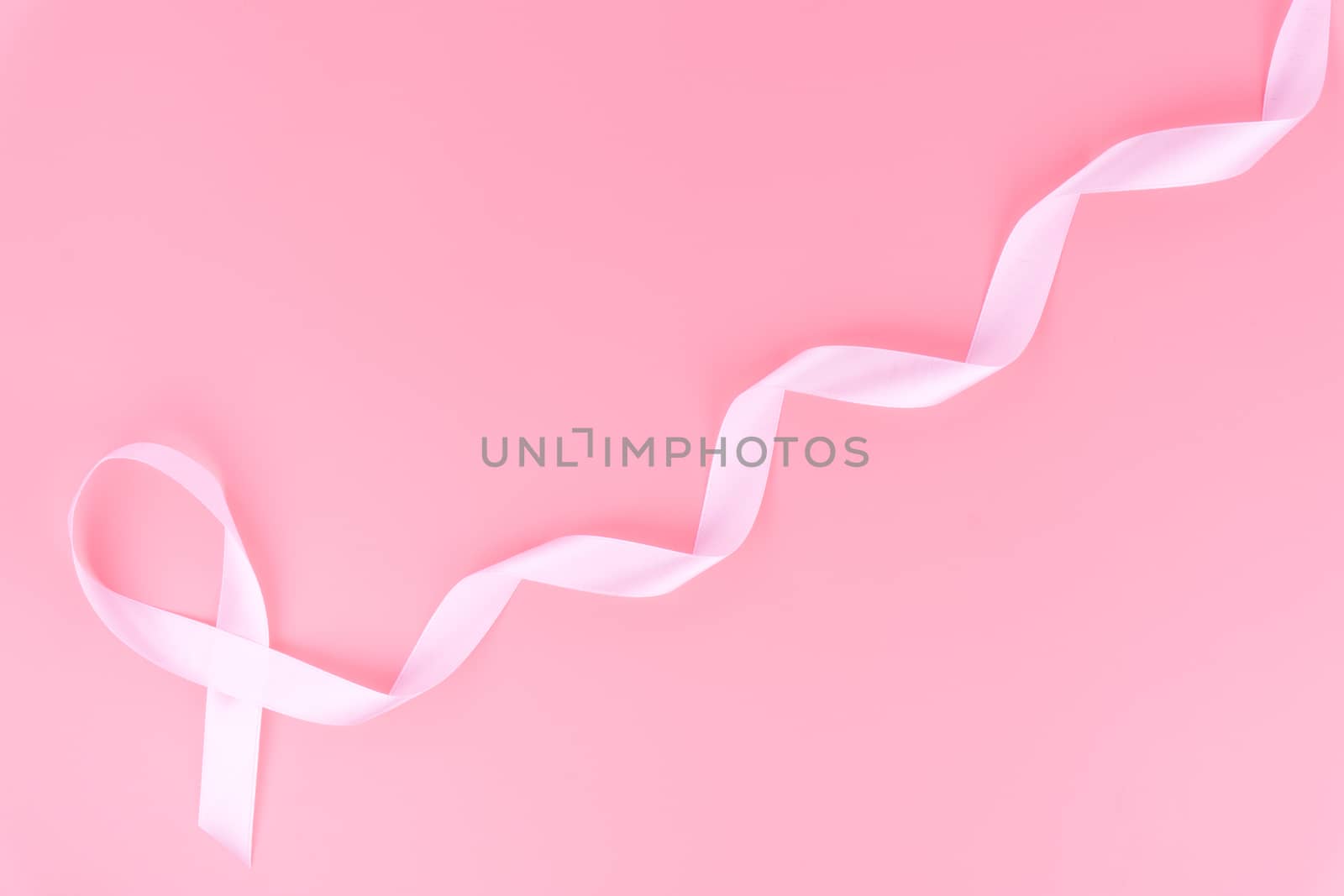 Pink ribbon breast cancer on pink background with copy space for text. Flat lay, top view.