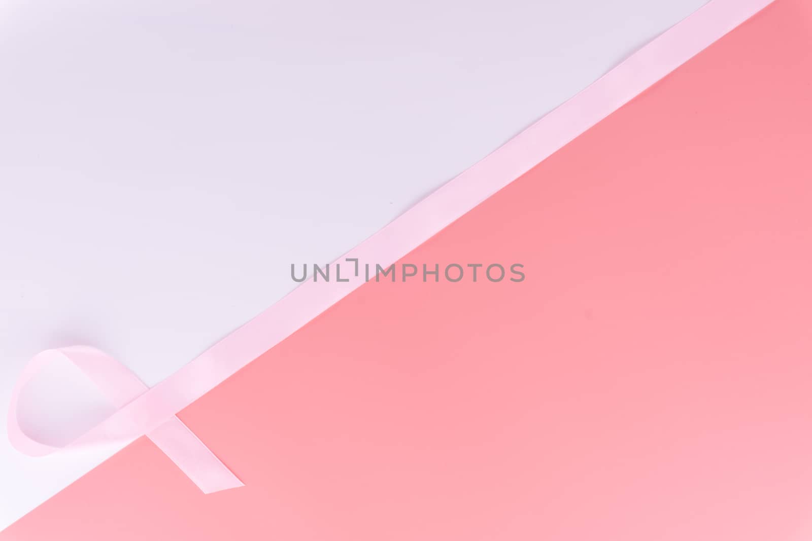Pink ribbon breast cancer on pink and white background with copy space for text. Flat lay, top view.