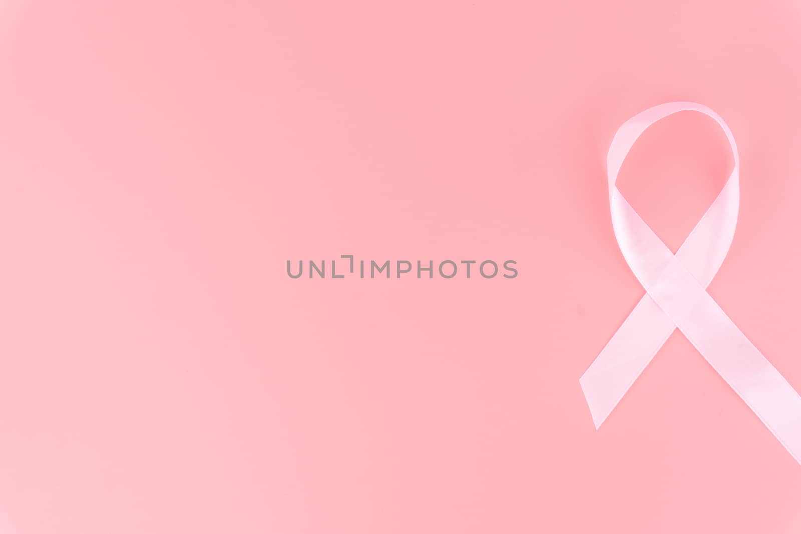 Pink ribbon breast cancer on pink background with copy space for text. Flat lay, top view.