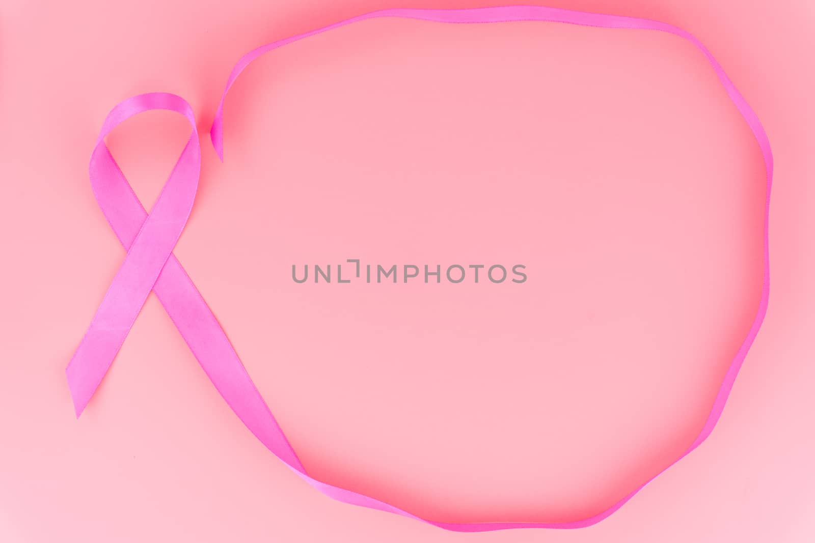 Pink ribbon breast cancer on pink background with copy space for text. Flat lay, top view.