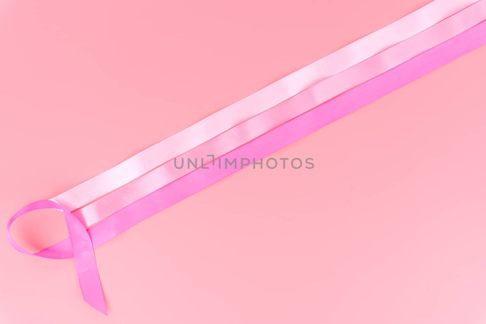 Pink ribbon breast cancer on pink background with copy space for text. Flat lay, top view.