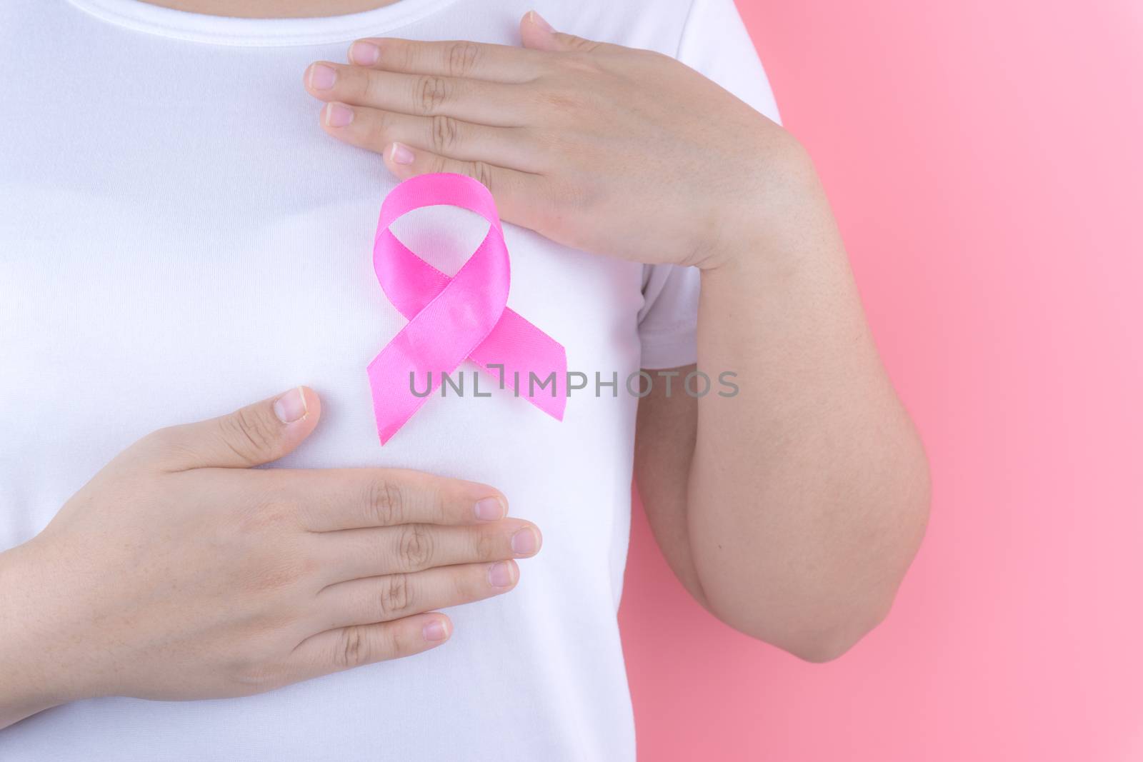 Healthcare, medicine and breast cancer awareness concept. Closeup on woman chest with pink breast cancer awareness ribbon.