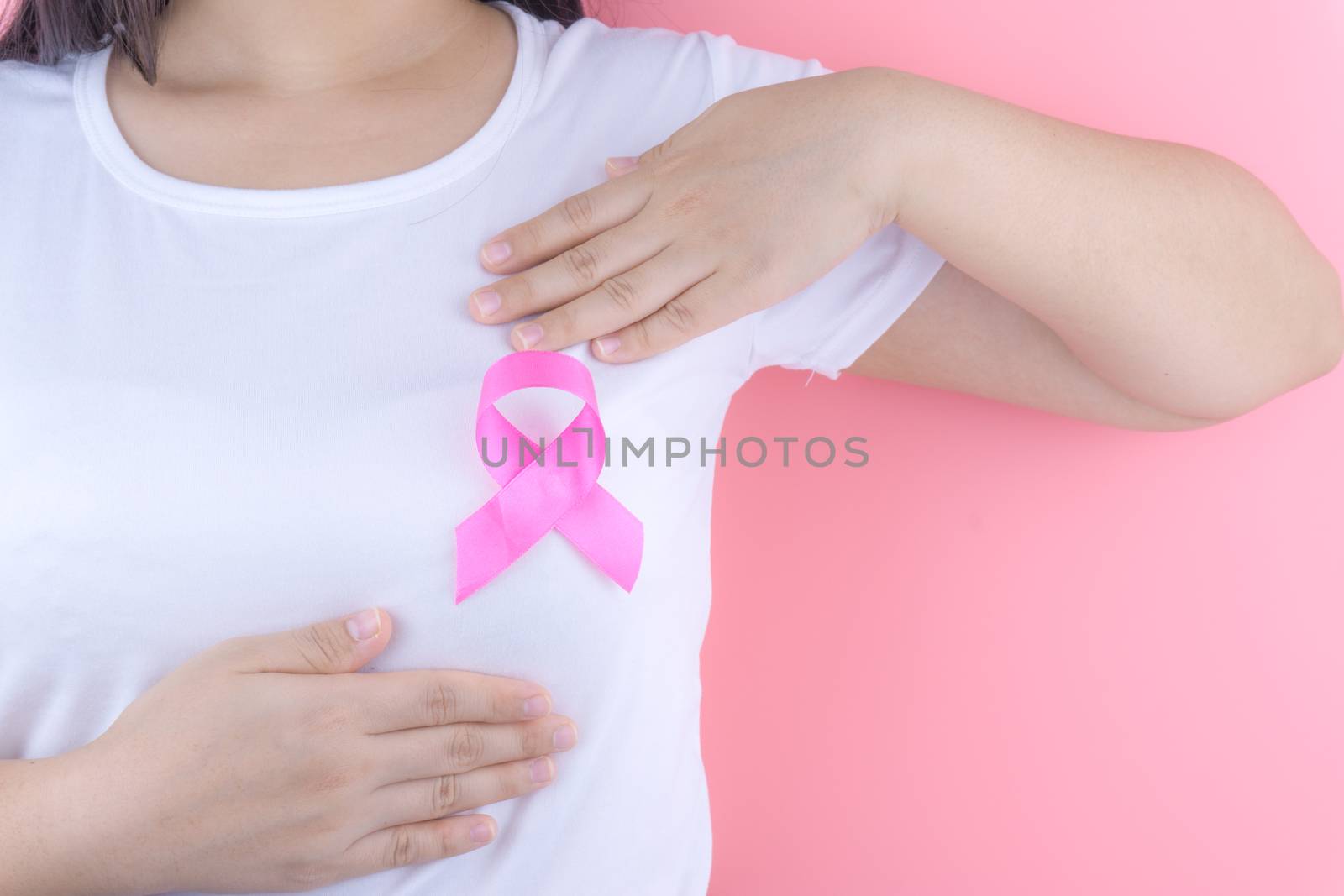 Healthcare, medicine and breast cancer awareness concept. Closeup on woman chest with pink breast cancer awareness ribbon.