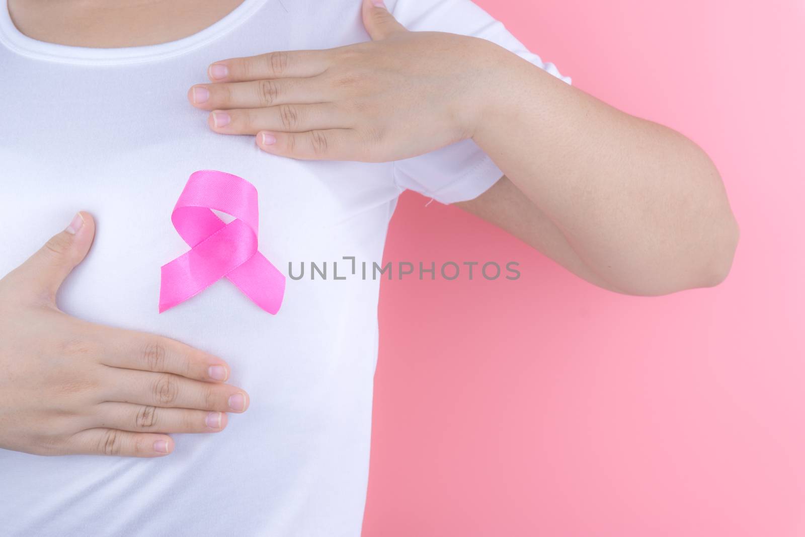Healthcare, medicine and breast cancer awareness concept. Closeup on woman chest with pink breast cancer awareness ribbon.