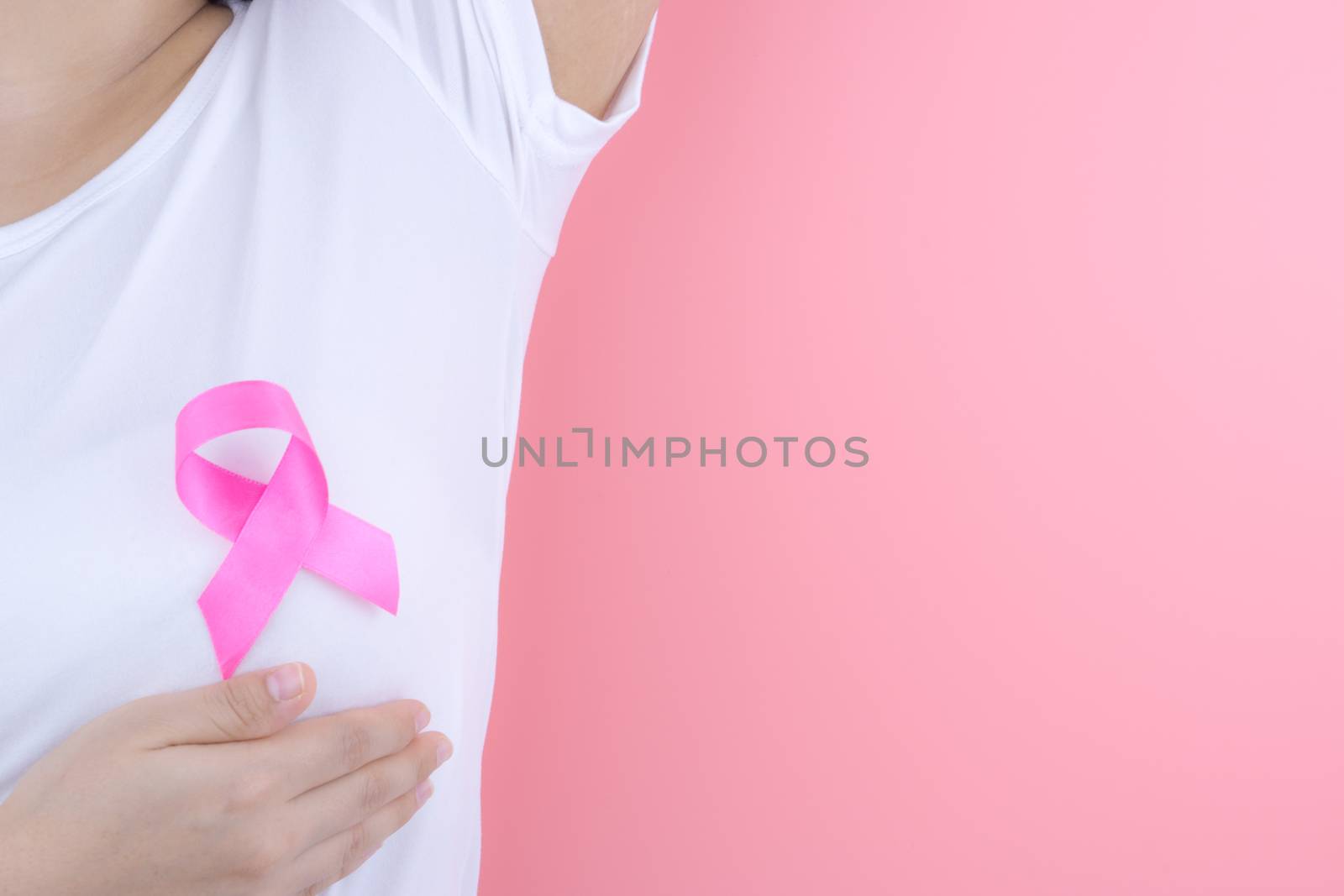 Healthcare, medicine and breast cancer awareness concept. Closeup on woman chest with pink breast cancer awareness ribbon.