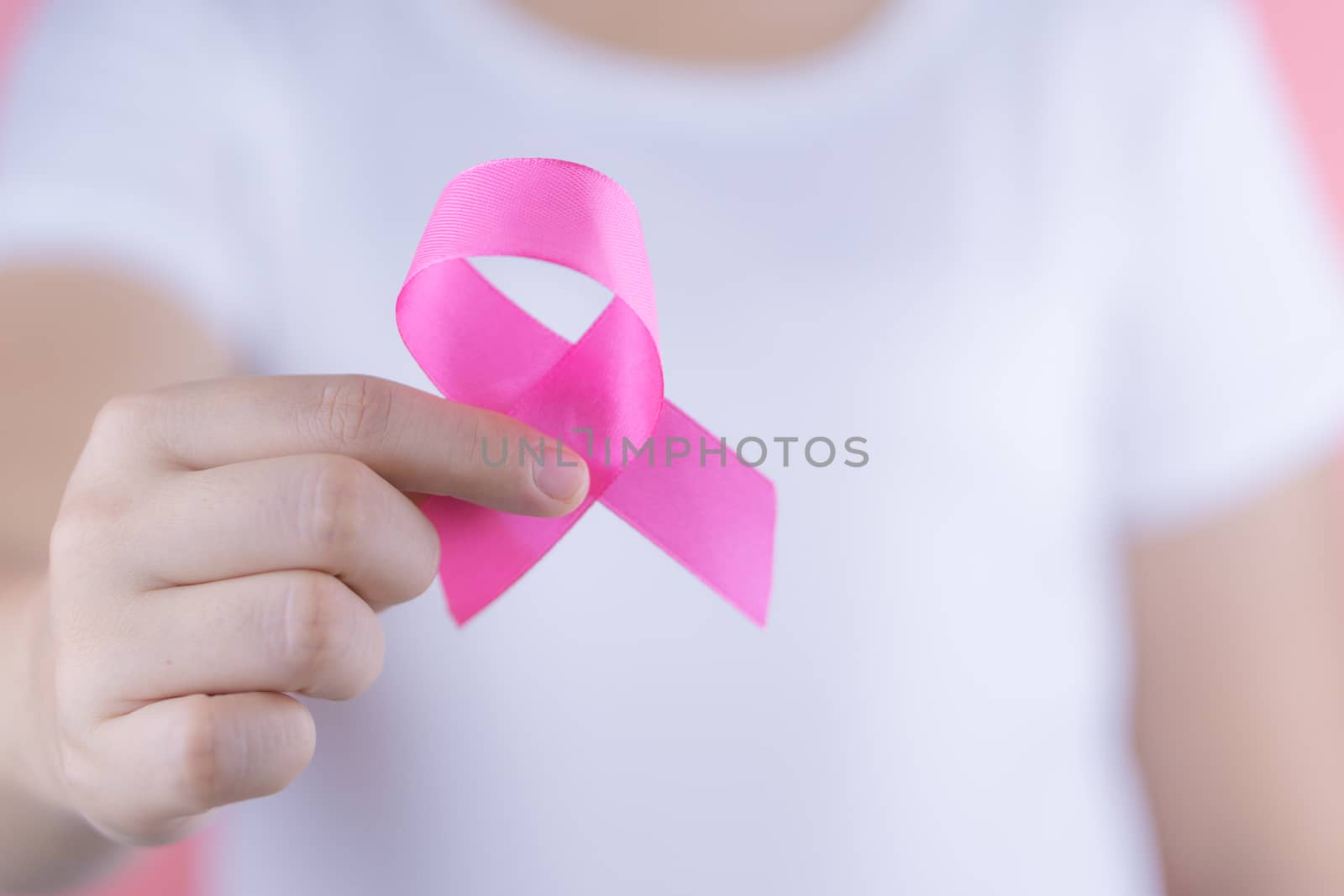 Healthcare, medicine and breast cancer awareness concept. Closeup woman hands holding pink breast cancer awareness ribbon.