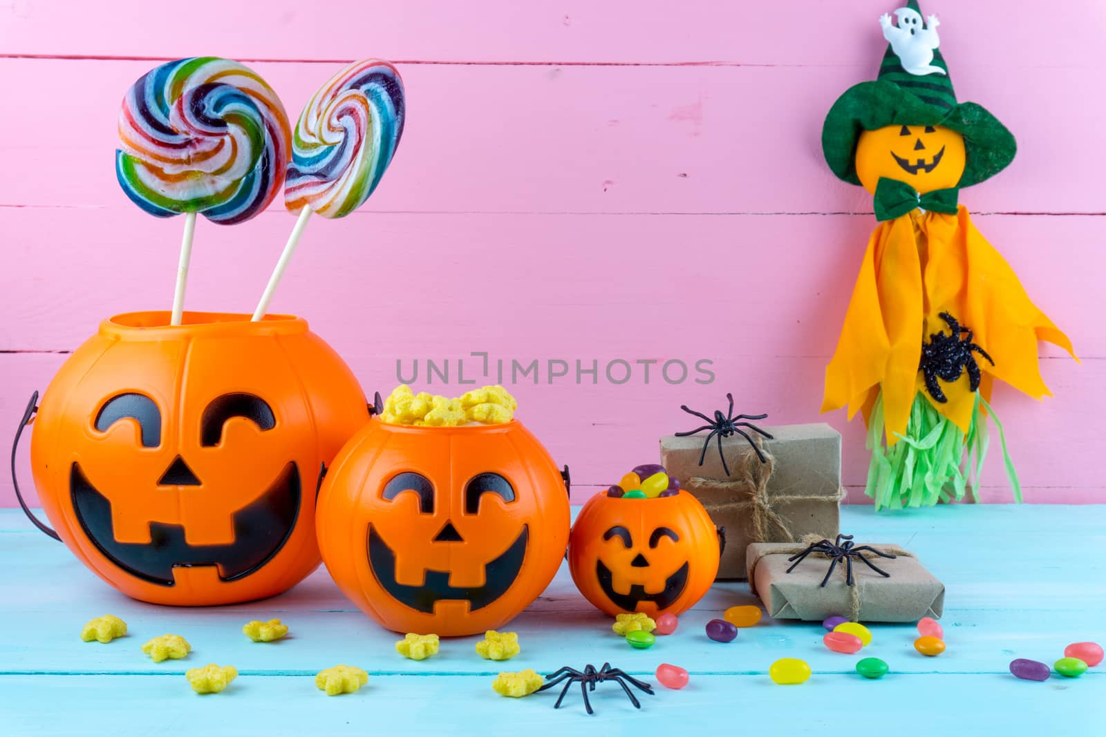 Trick or Treat - Halloween jack o' lantern, candy and rainbow lollipop on pink and blue wooden background with copy space for text. Flat lay, top view