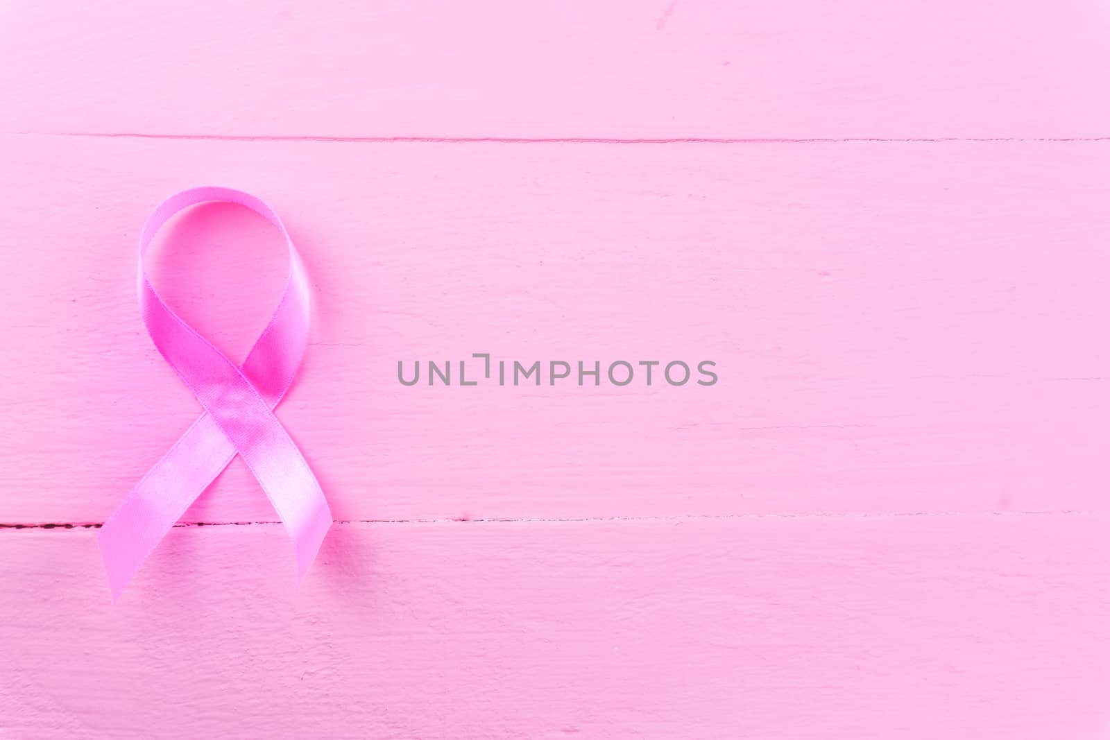 Healthcare, medicine concept. Pink breast cancer awareness ribbon on pink wooden background with copy space for text. Flat lay, top view