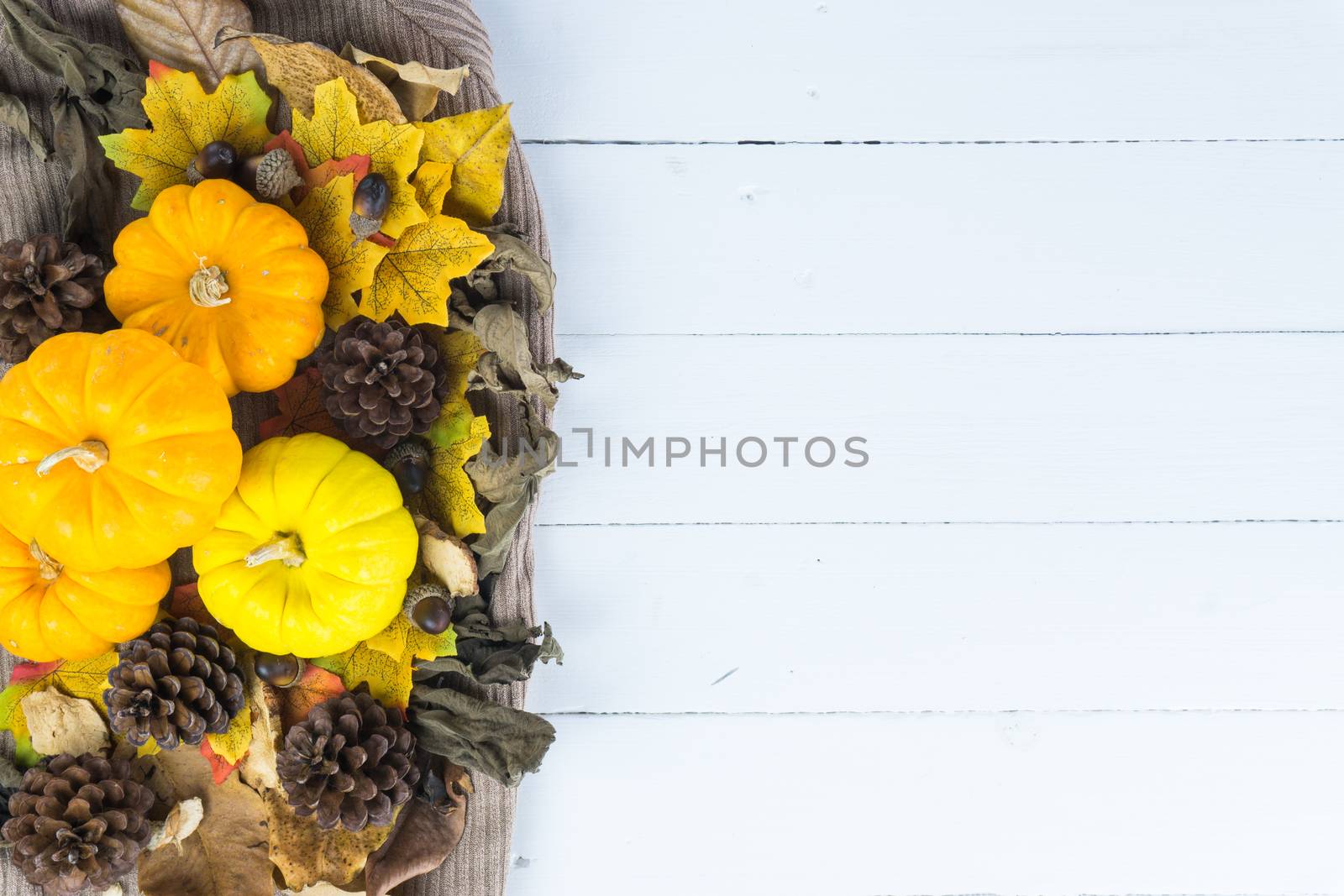 Top view of Autumn maple leaves with pumpkin and pine cone on white wooden background. Thanksgiving day concept. Halloween day.