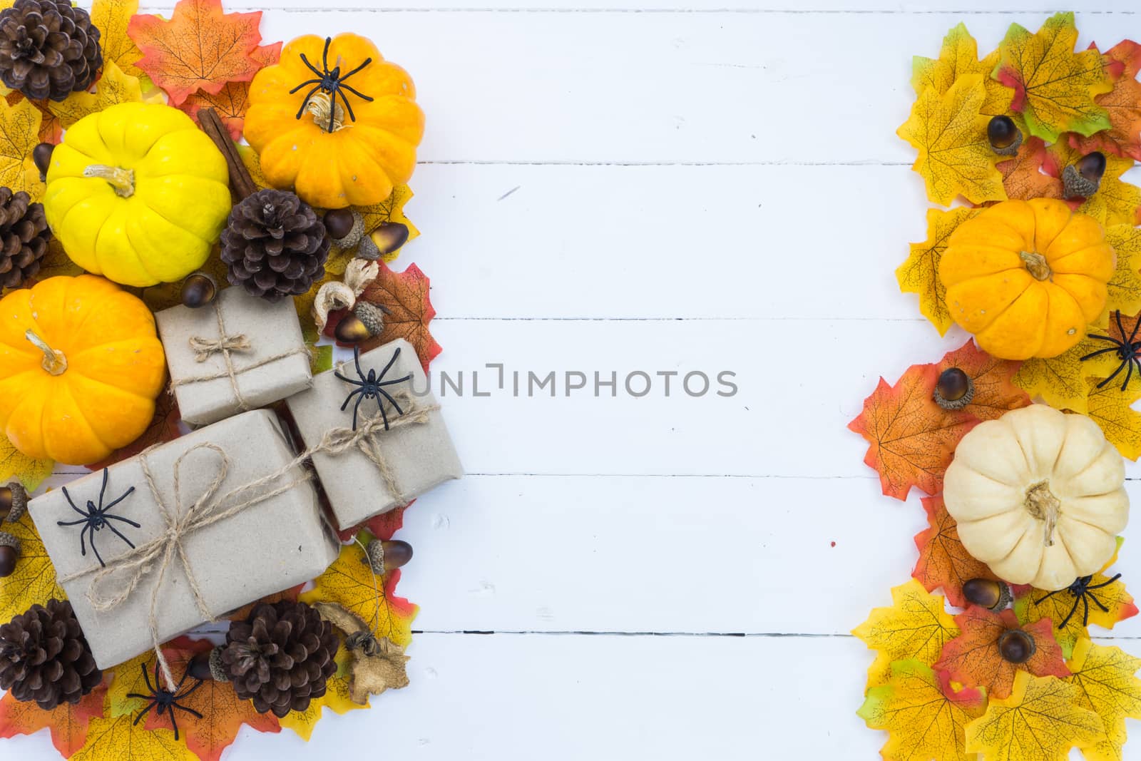 Halloween holiday background with orange pumpkin, ghost, spider and bat on white wooden table with copy space for text. Flat lay, top view
