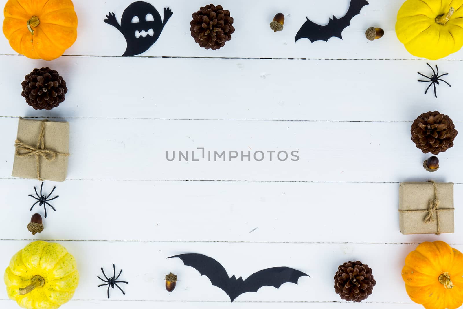 Halloween holiday background with orange pumpkin, ghost, spider and bat on white wooden table with copy space for text. Flat lay, top view