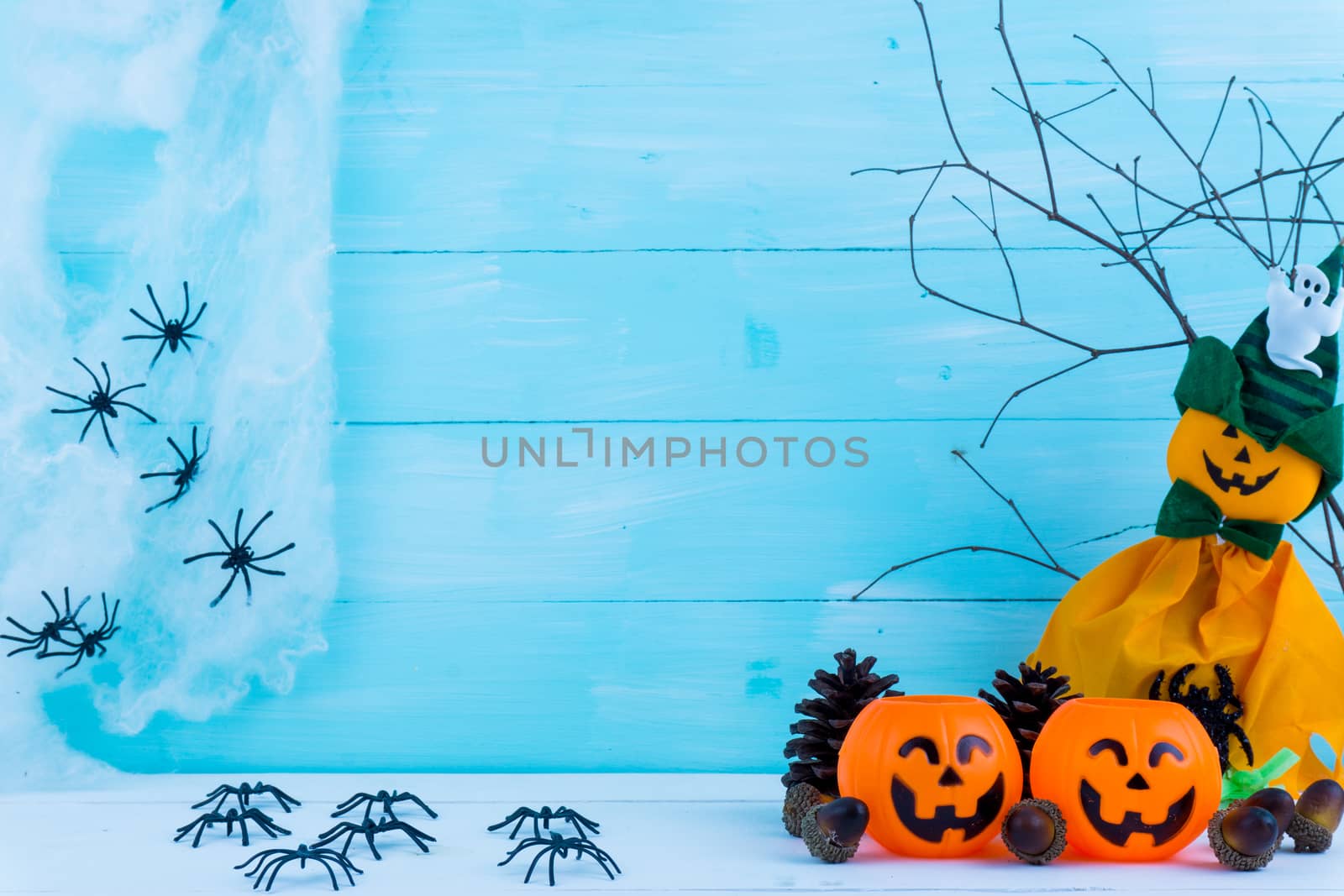 Halloween holiday background with spider, webs, gifts and jack lantern on blue wooden table with copy space for text. Flat lay, top view