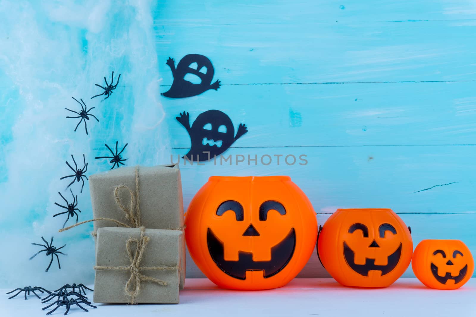 Halloween holiday background with spider, webs, gifts and jack lantern on blue wooden table with copy space for text. Flat lay, top view