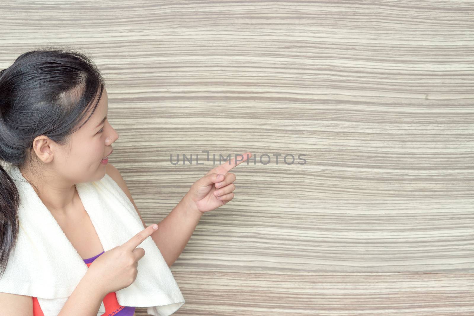 Young woman standing and pointing finger at copy space wooden ba by mikesaran