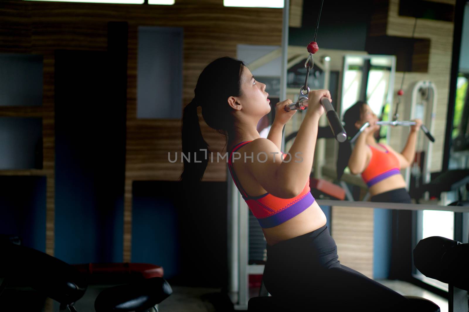 Asian beauty woman doing exercise for back. Working out on a lat pulldown machine. Diet, weight loss, slim body, healthy lifestyle concept.