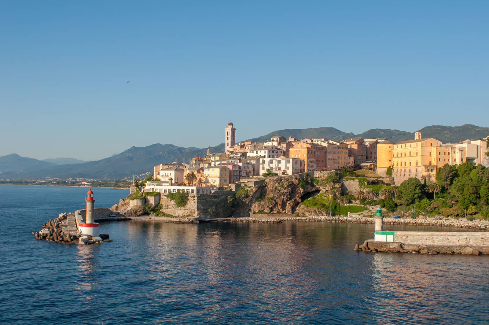 port of Bastia early in the morning in Corsica. The sea is calm, two lighthouses and the city of Bastia in the background