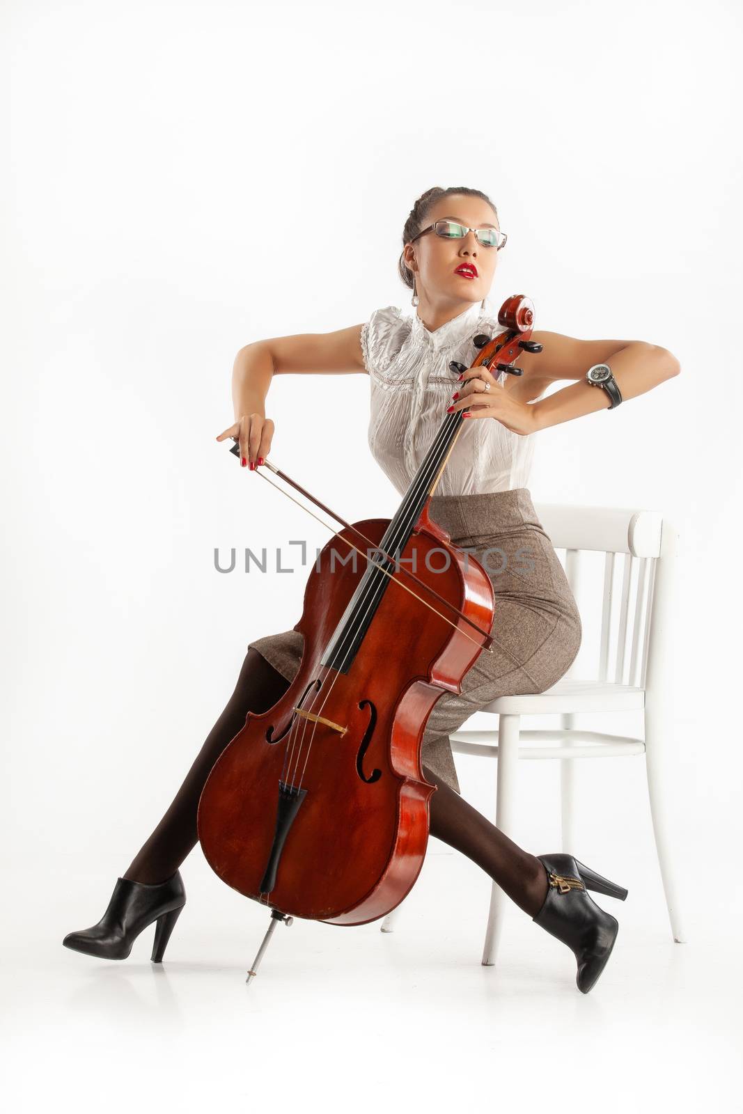 Young woman playing on a cello on an isolated studio background