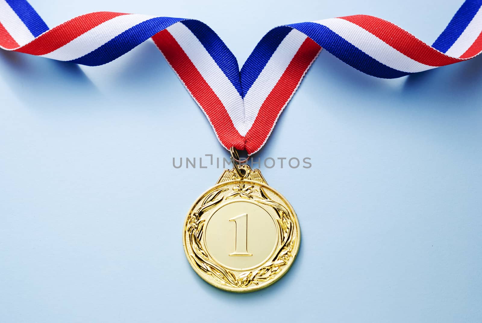 Gold medal 1 place with a ribbon on a light blue background, the concept of victory or success