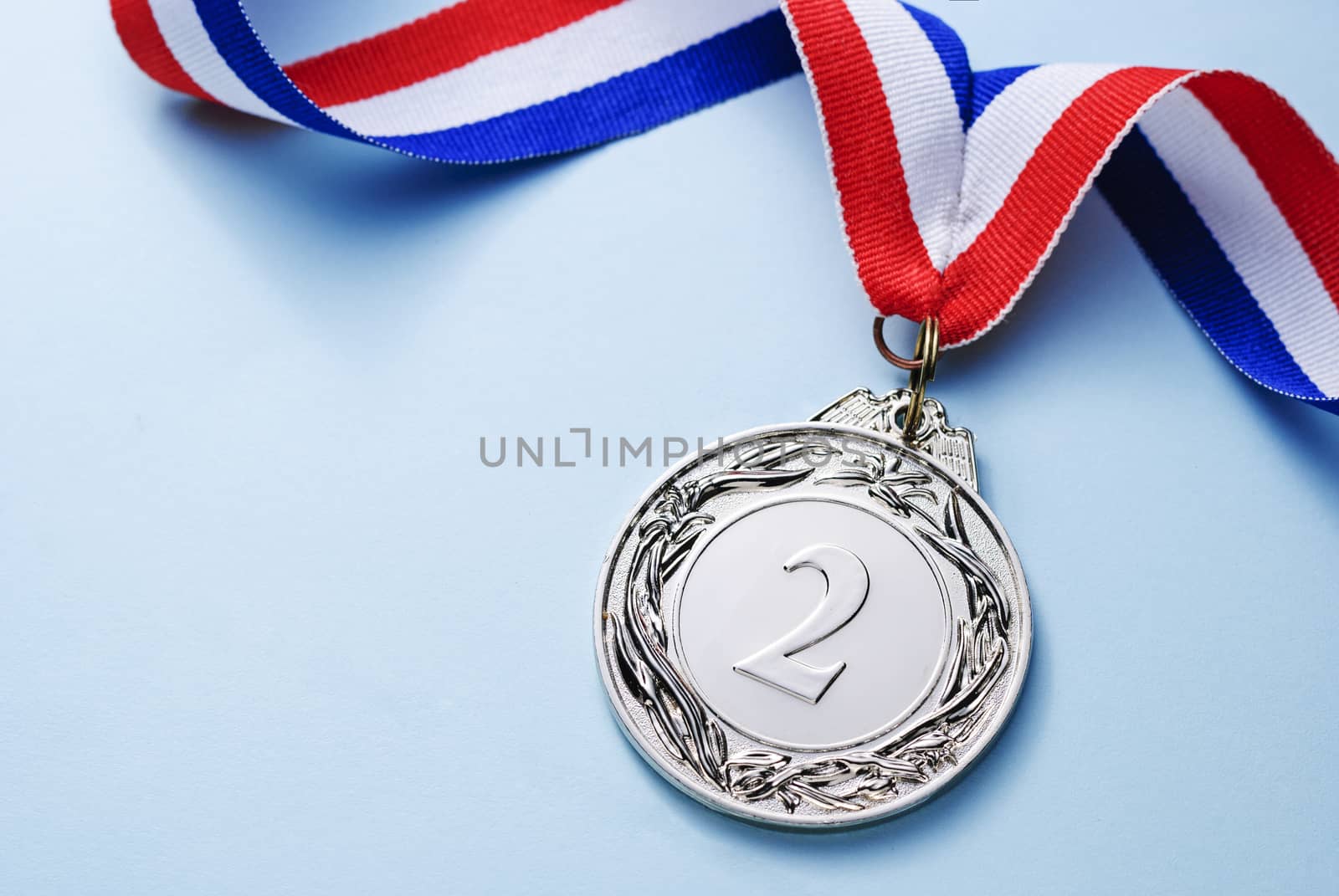 Silver medal 2 place with ribbon on a light blue background, the concept of victory or success