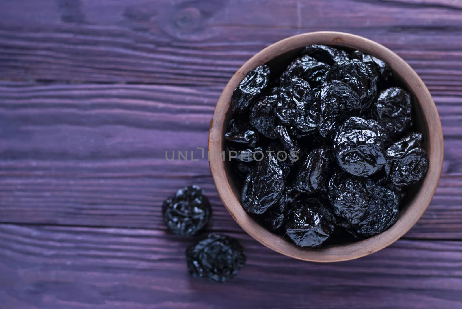 Clay bowl filled with juicy prunes by sergii_gnatiuk