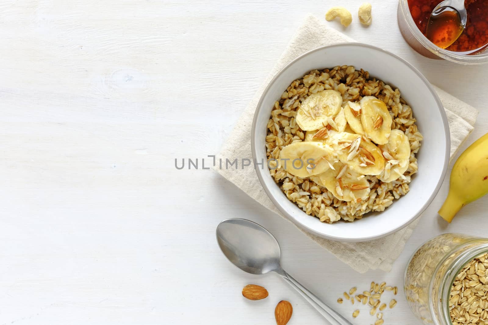 Flat lay view of breakfast set with banana oatmeal in bowl against white table with copy space