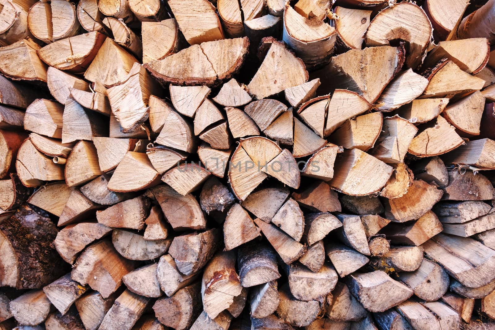 Background texture of chopped wood or logs end on in a stack for winter fuel in a full frame view