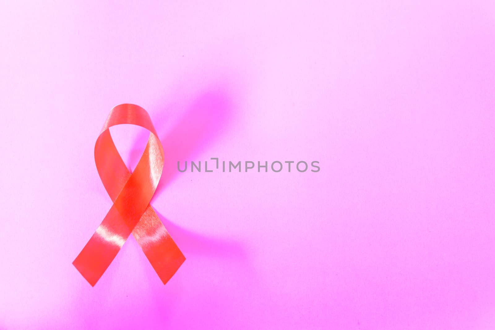 Red Ribbon Support HIV, AIDS on pink background and copy space for use