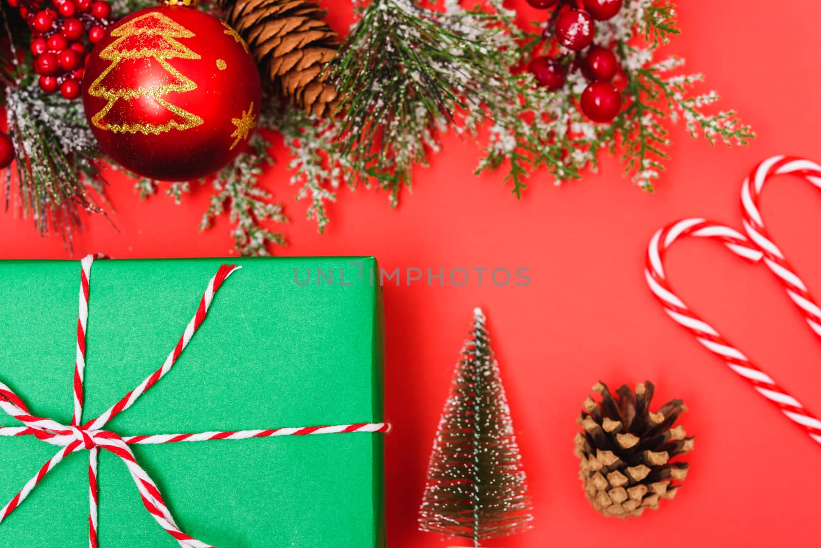 Christmas green gift box and decorations, fir tree branches on red background. Merry Christmas concept. With Copy space for text
