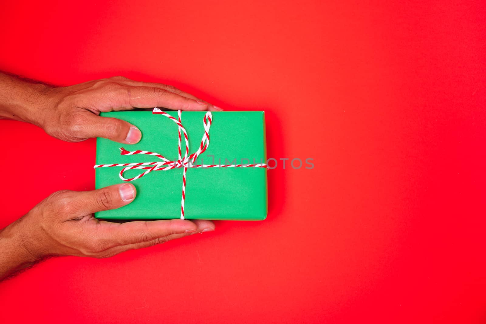 Happy New Year and Christmas 2020 or valentine day, top view hands with green gift box on red background with copy space for your text