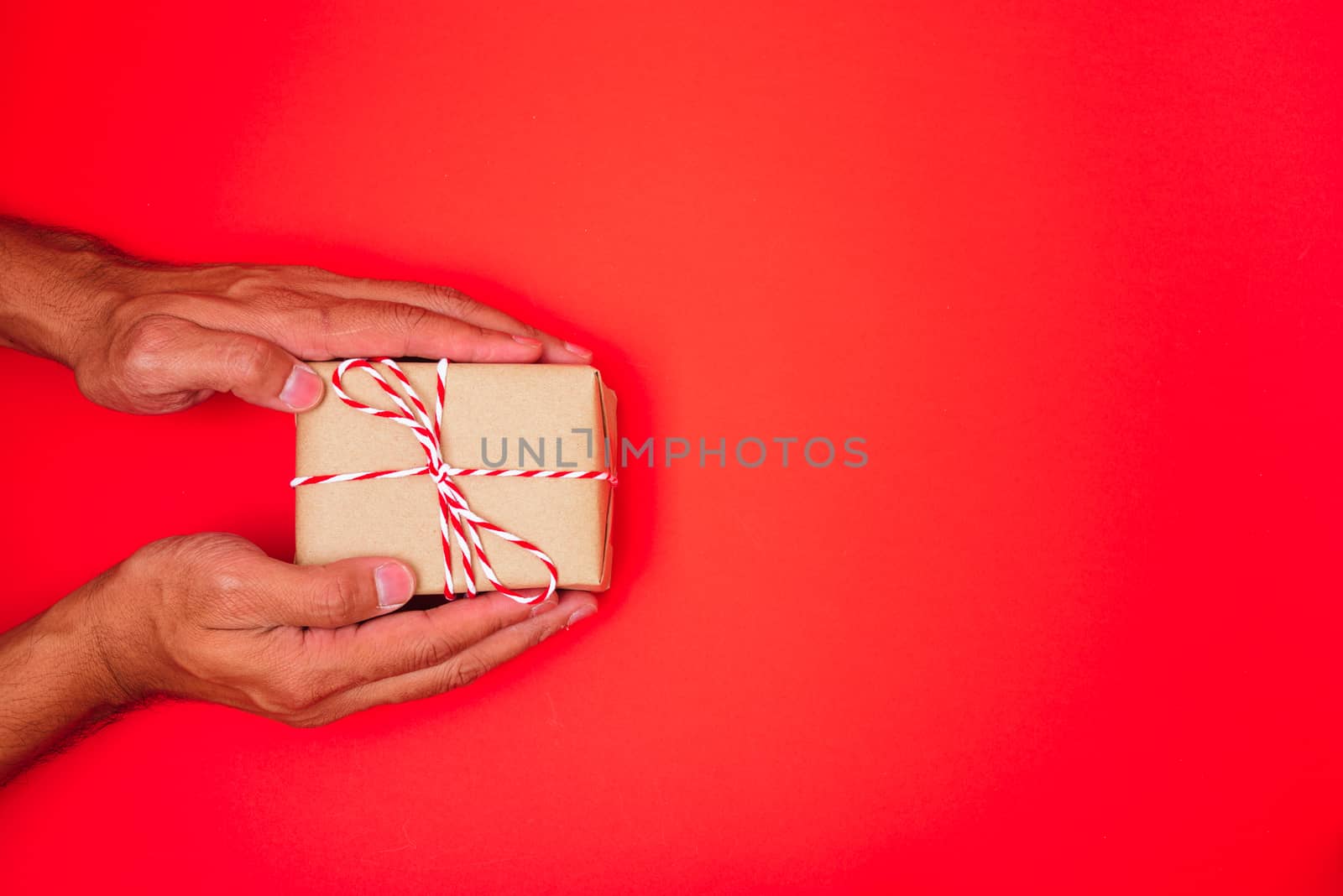 Happy New Year and Christmas 2020 or valentine day, top view hands with Brown gift box on red background with copy space for your text