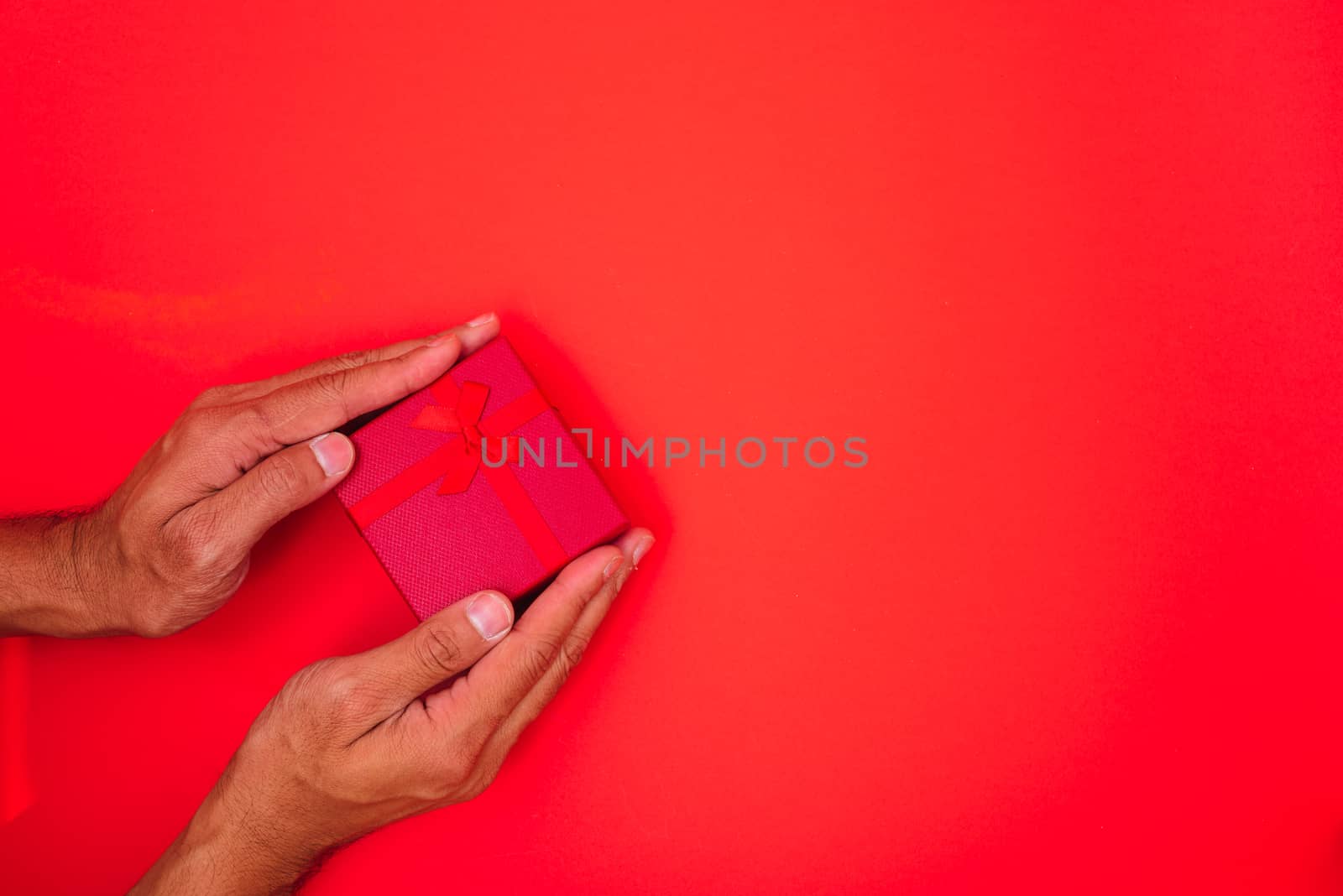 Happy New Year and Christmas 2020 or valentine day, top view hands with red gift box on red background with copy space for your text