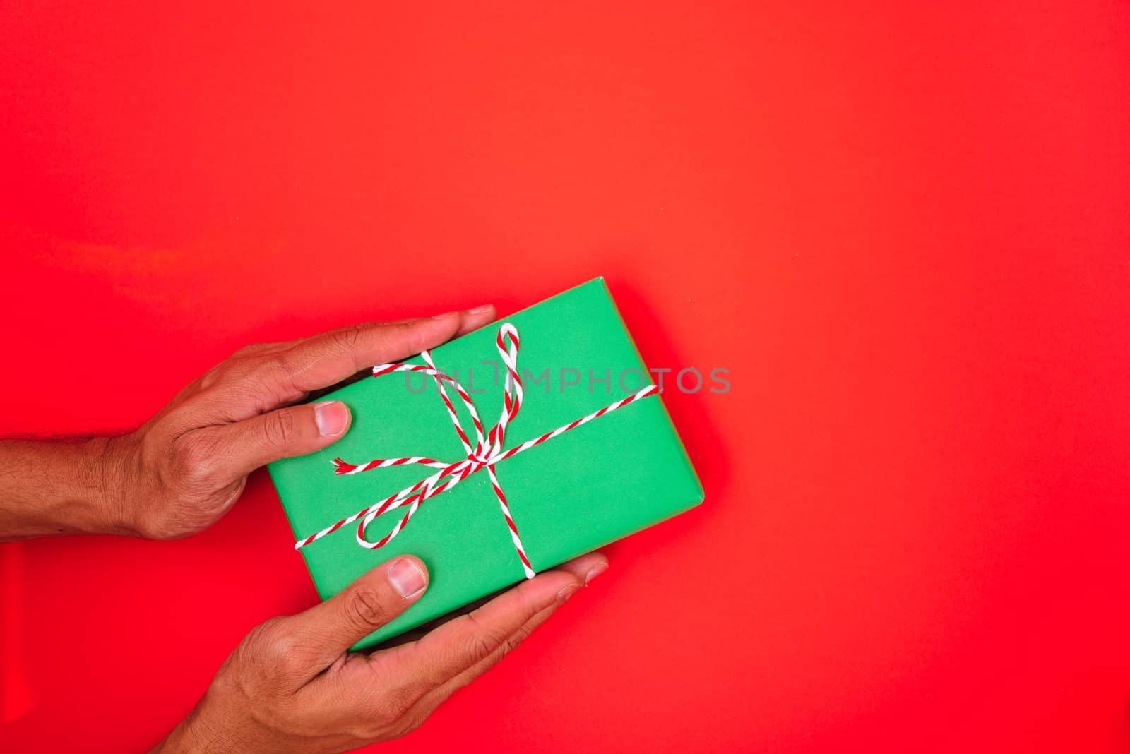 Happy New Year and Christmas 2020 or valentine day, top view hands with green gift box on red background with copy space for your text