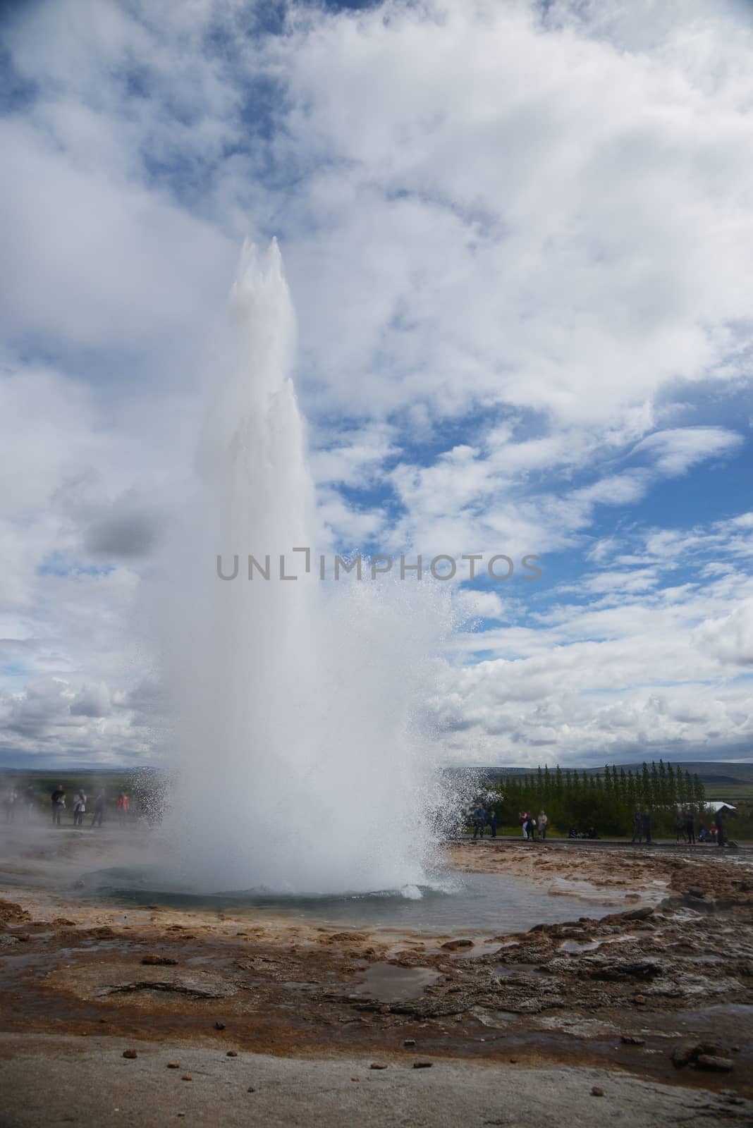 Strokkur geyser eruption in Iceland with blue sky and clouds