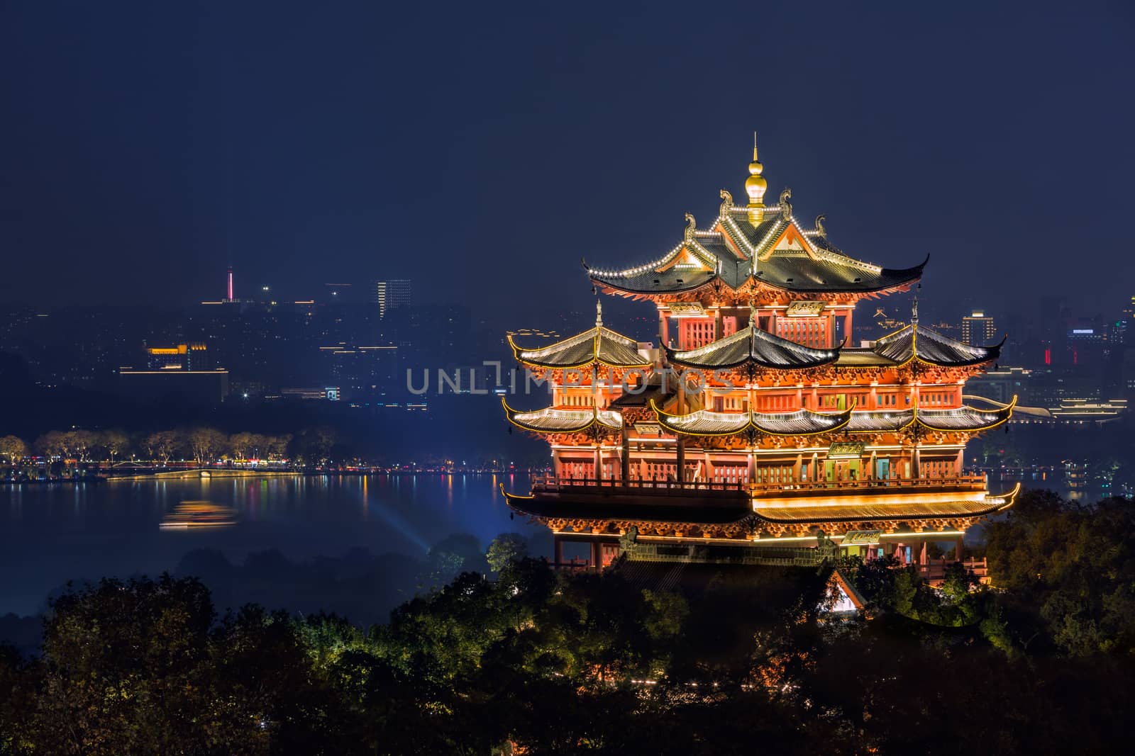 Night view of illuminated Cheng Huang Ge (City God Pavillion) with West Lake and city skyline on background, Hangzhou, China