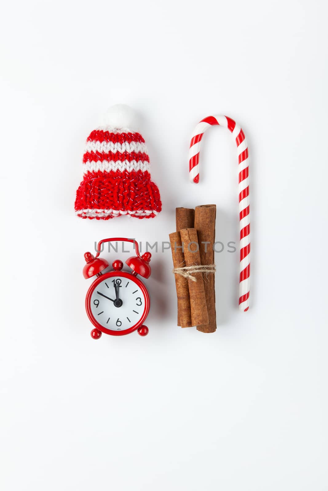 Christmas composition, cane candy, small analog clock, striped hat on white background. Minimal style. Top view. Festive, holiday concept. For social media, greeting card.