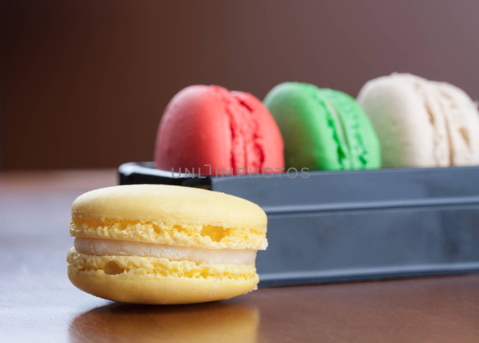 Close-up on yellow macaroons with red, green and beige macarons cakes on background