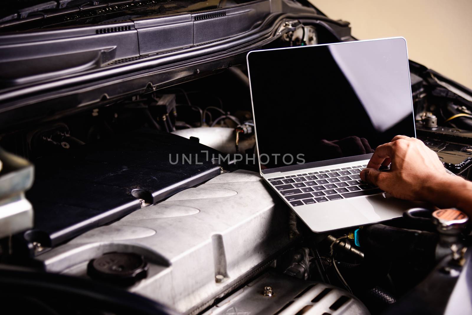 Professional car repair or maintenance mechanic engine working service with laptop computer at workshop