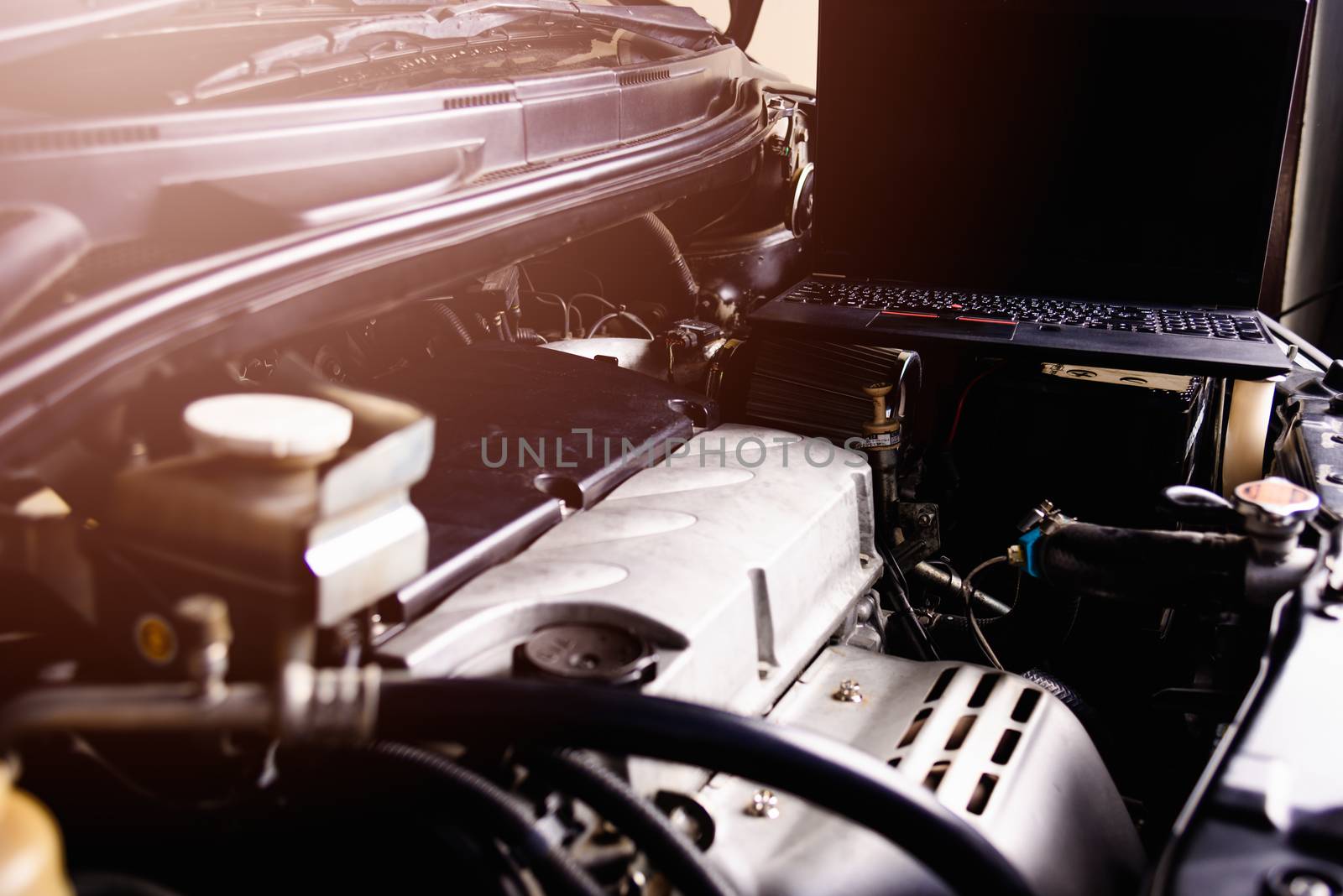 Laptop computer on car mechanic engine for service at workshop