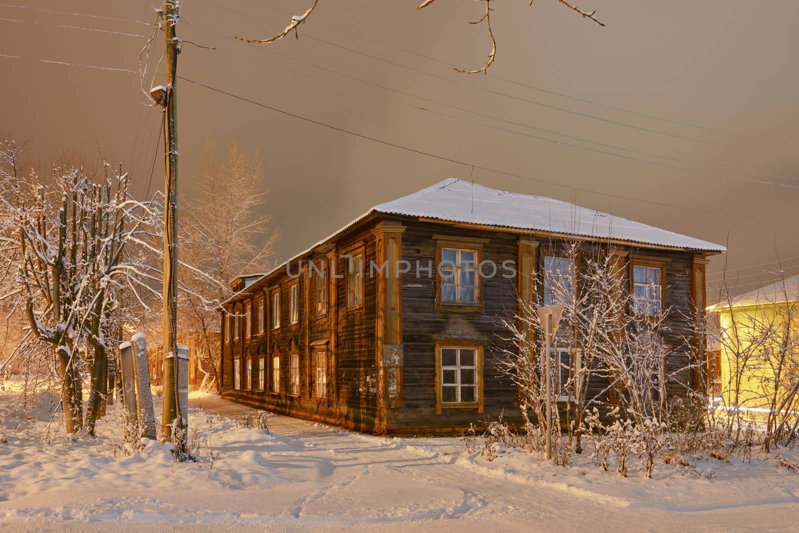 Winter street in night illumination with an old house in the foreground