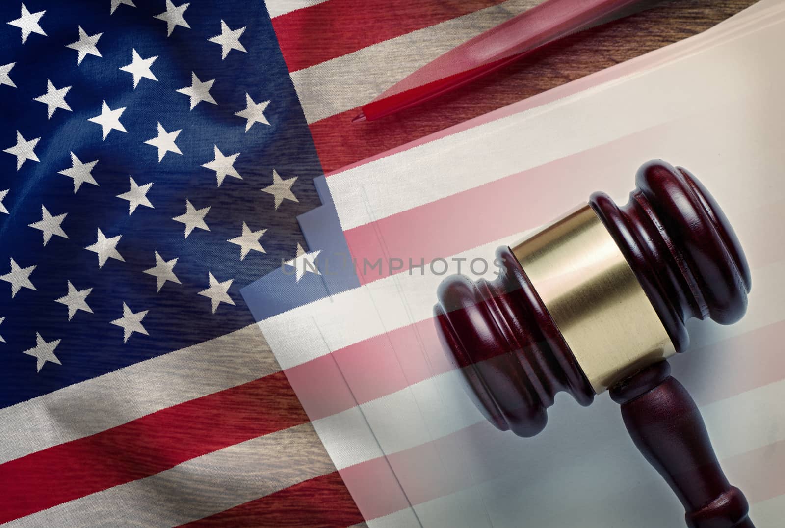 Judges gavel on a legal document with pen overlaid with the United States flag conceptual of law enforcement in America