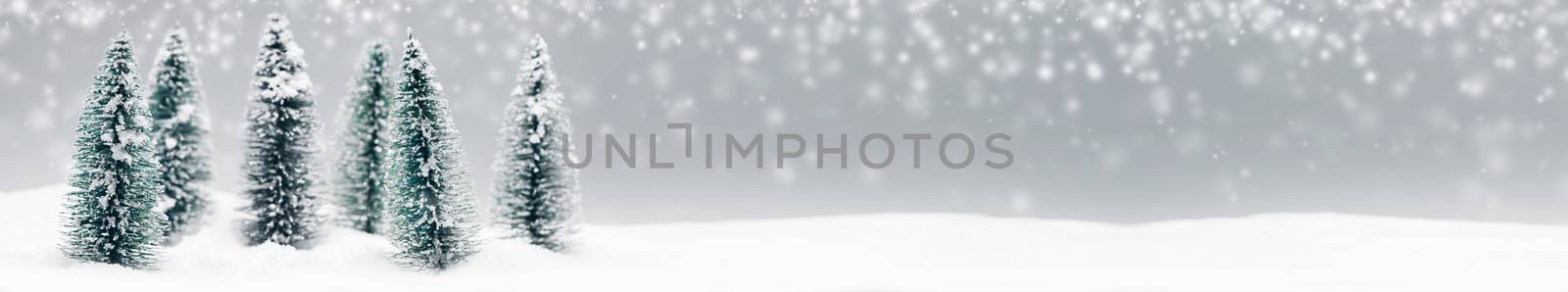 Winter wonderland with small decorative fir trees at snowfall, winter holidays concept