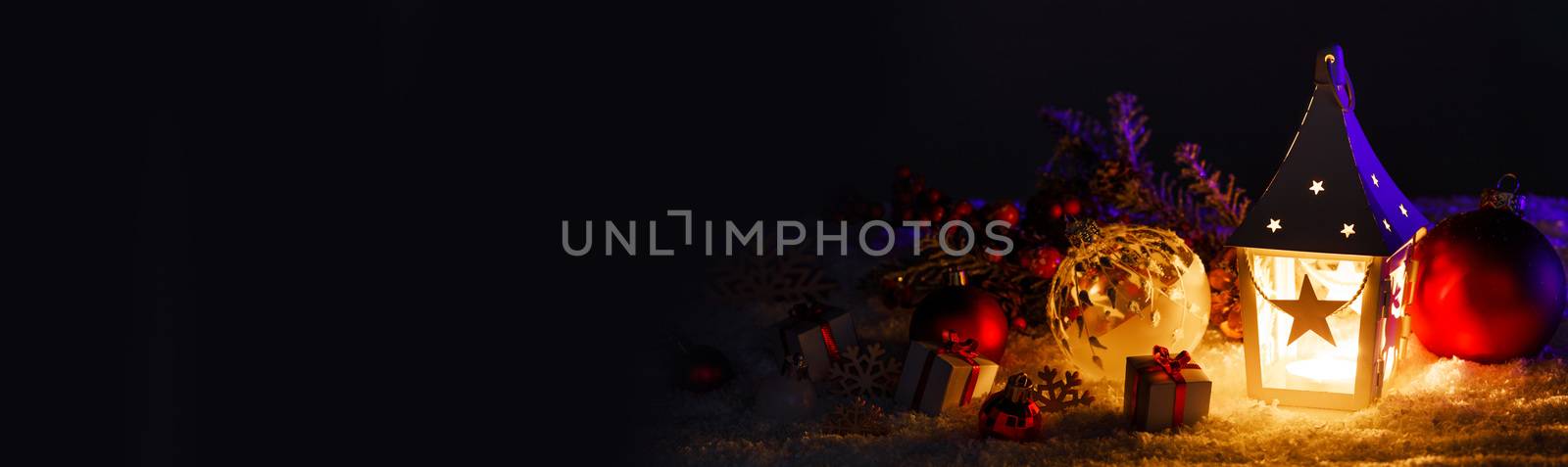 Christmas holidays card with gifts , balls and glowing lantern in snow over black background
