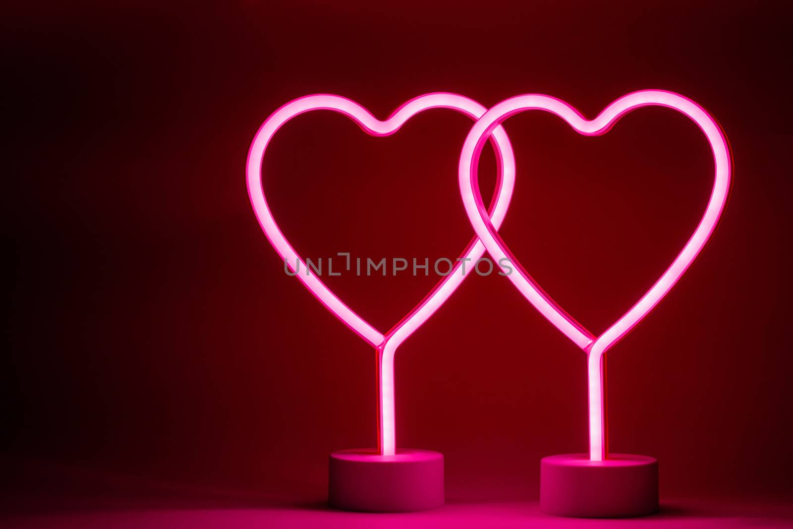 Two glowing pink neon hearts Valentines day party concept