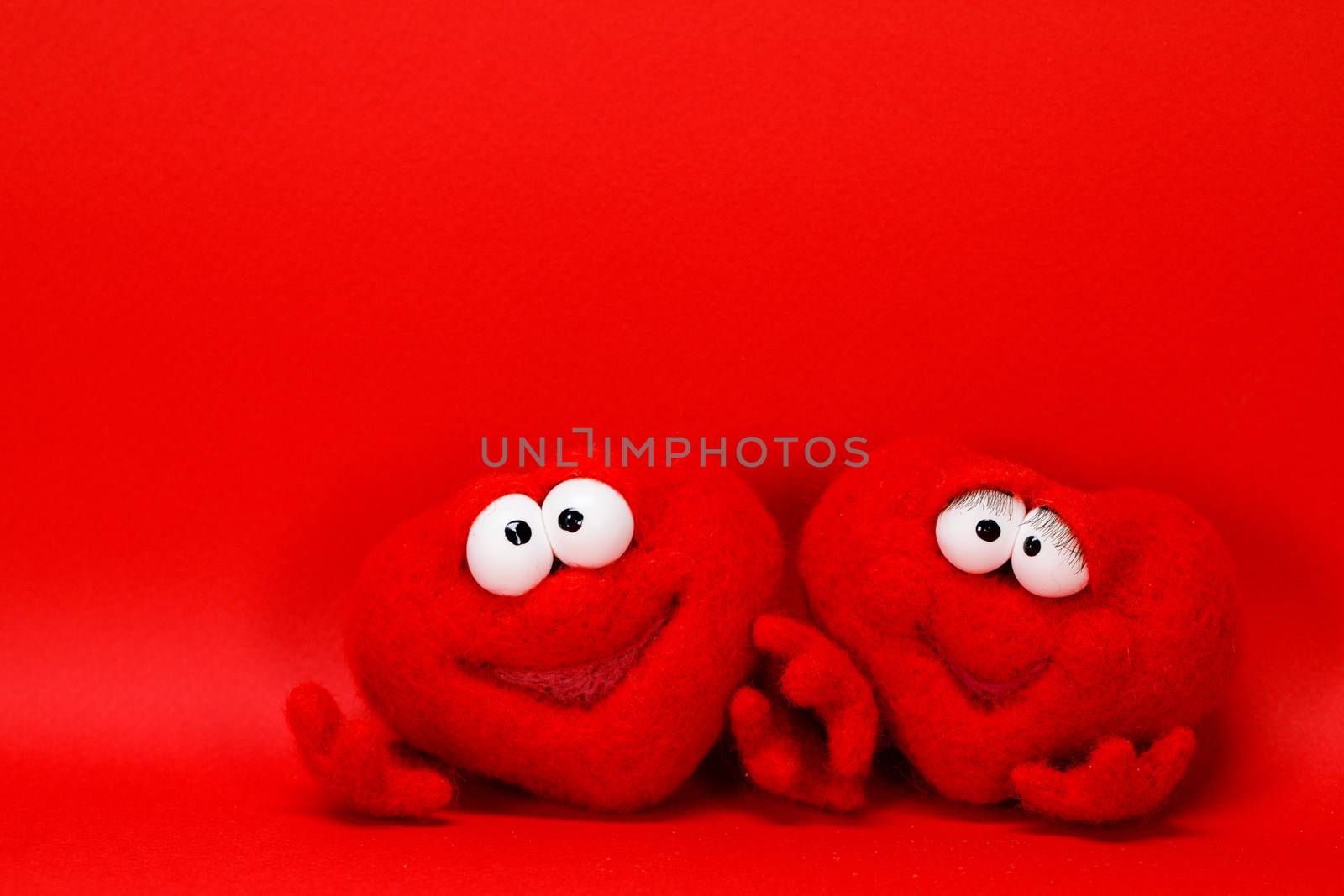 Two wool red hearts on red background with copy space for text, symbol of love, healtcare, valentines day concept