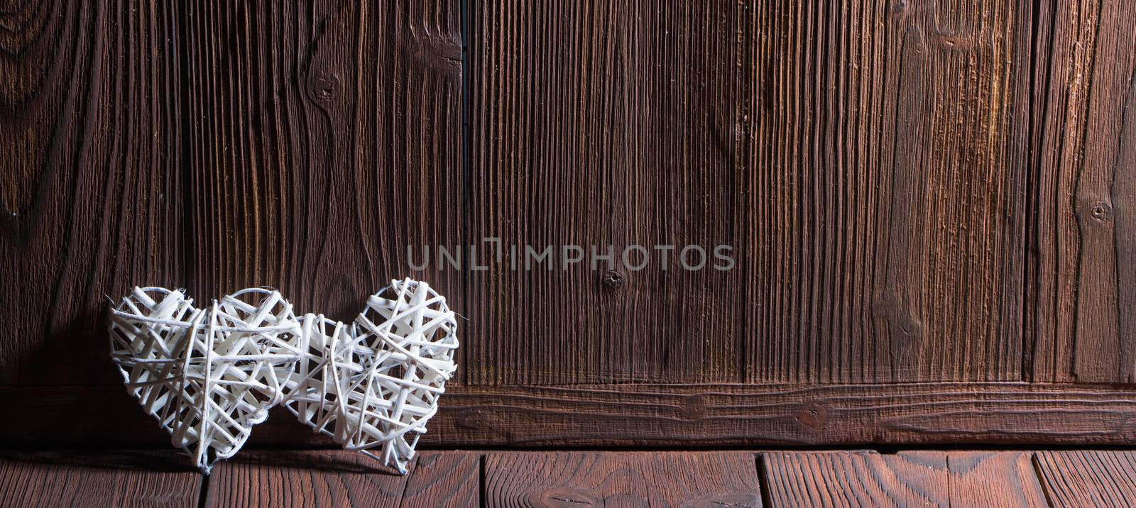 Two wicker hearts on wooden background with copy space for text